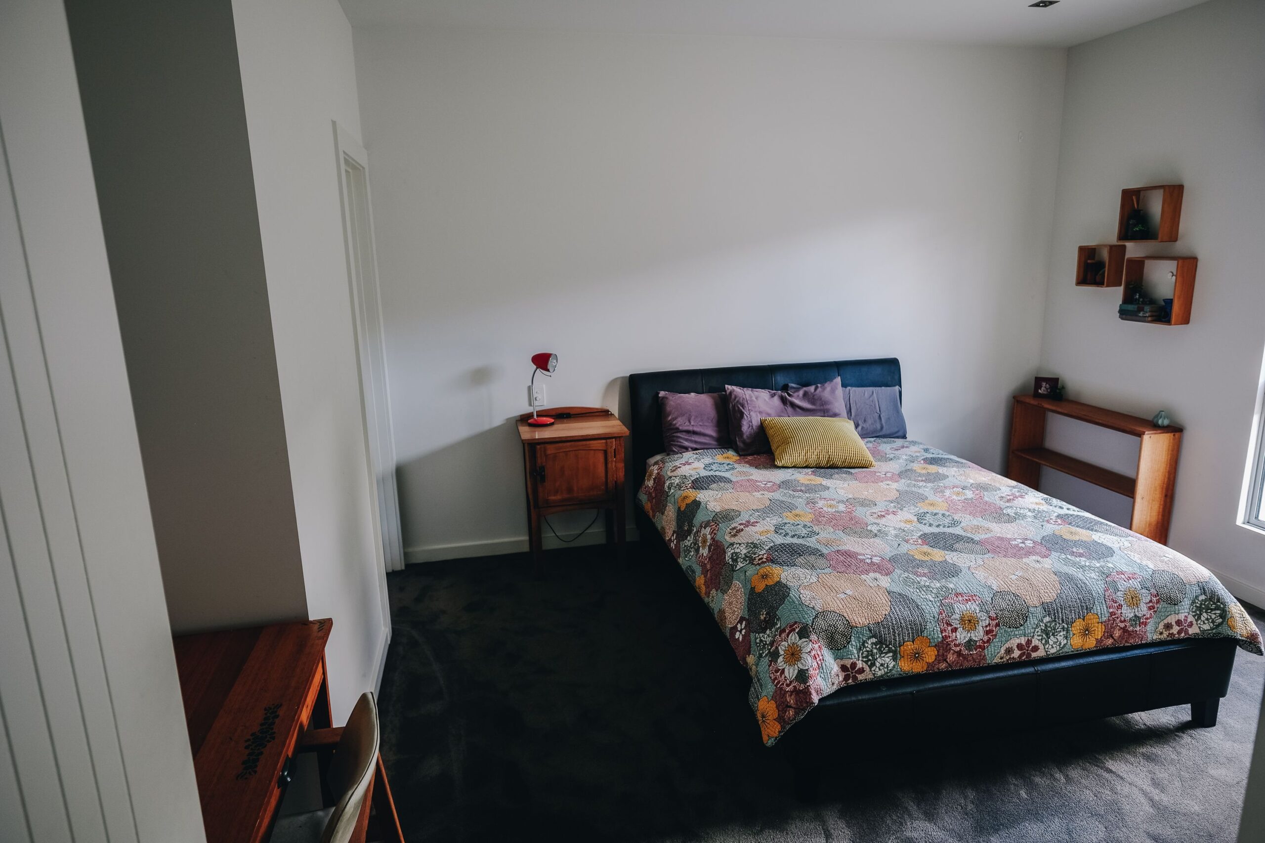 Cozy bed and wooden nightstand with shelves in a light bedroom
